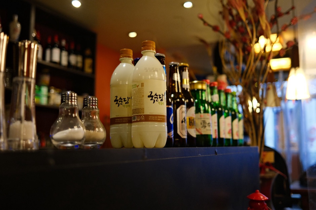 Traditional Korean soju bottle and small glass on a wooden table