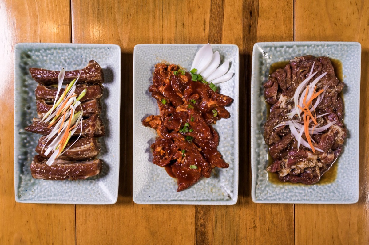 Mesa posta de um restaurante de churrasco coreano com diversos acompanhamentos