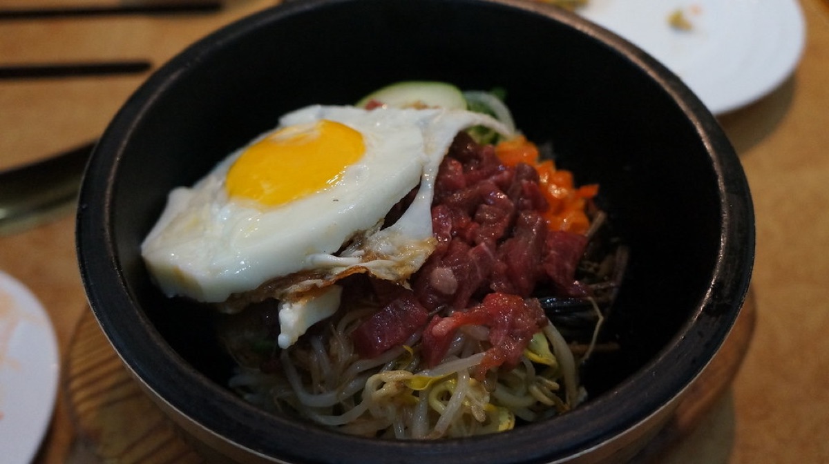 石鍋裡放著煎蛋、紅色牛肉和豆芽的拌飯
