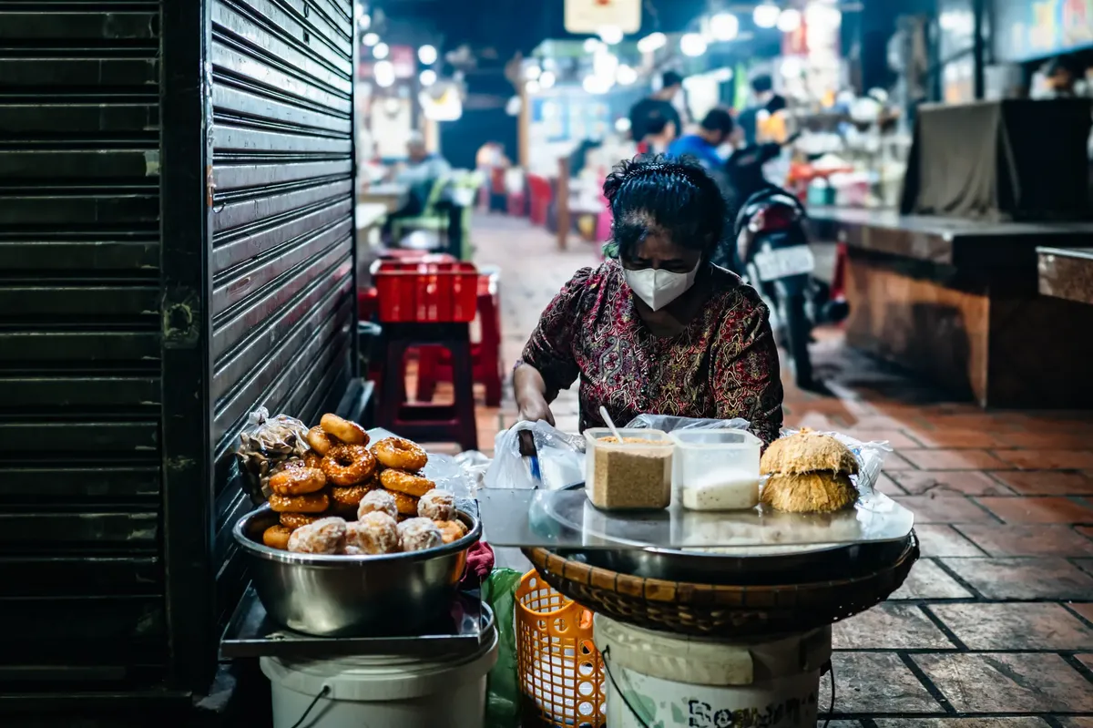 A street vendor preparing food in Phnom Penh's vibrant night market, showcasing bustling evening street life.