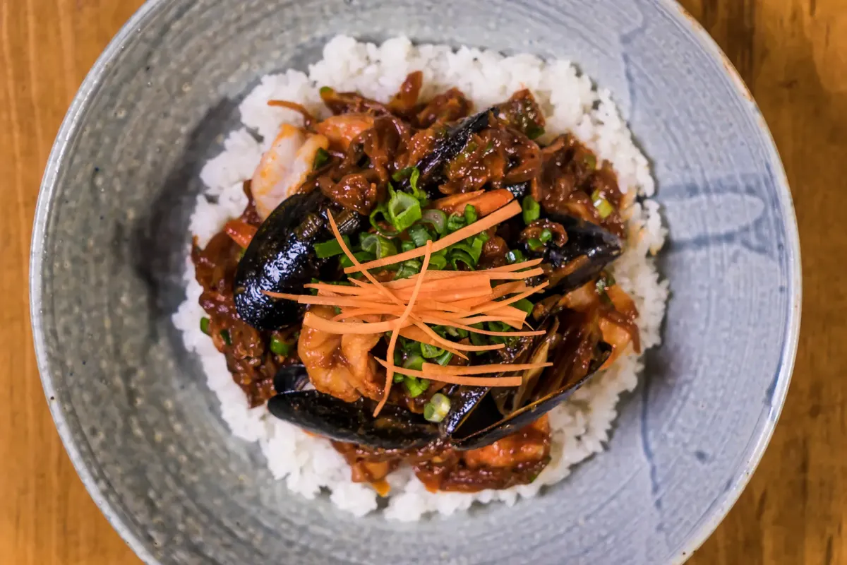 A close-up of a delicious Korean seafood rice bowl garnished with vegetables.