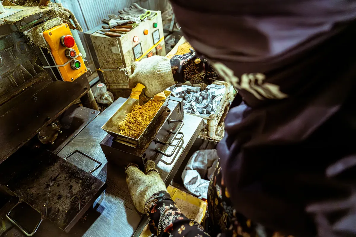 A person wearing gloves operating a machine in a food processing plant. Industrial setting.