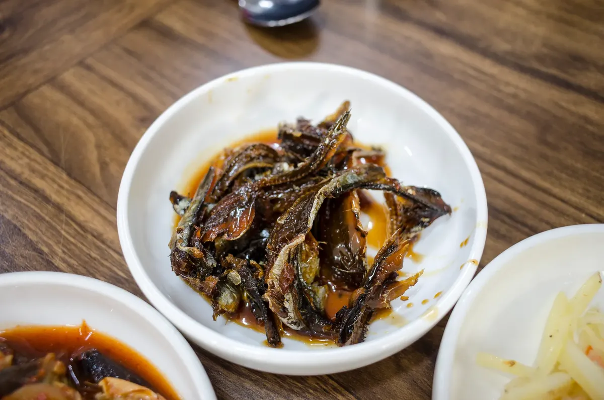 Appetizing Korean dried fish served on a ceramic plate, captured in high angle food photography.
