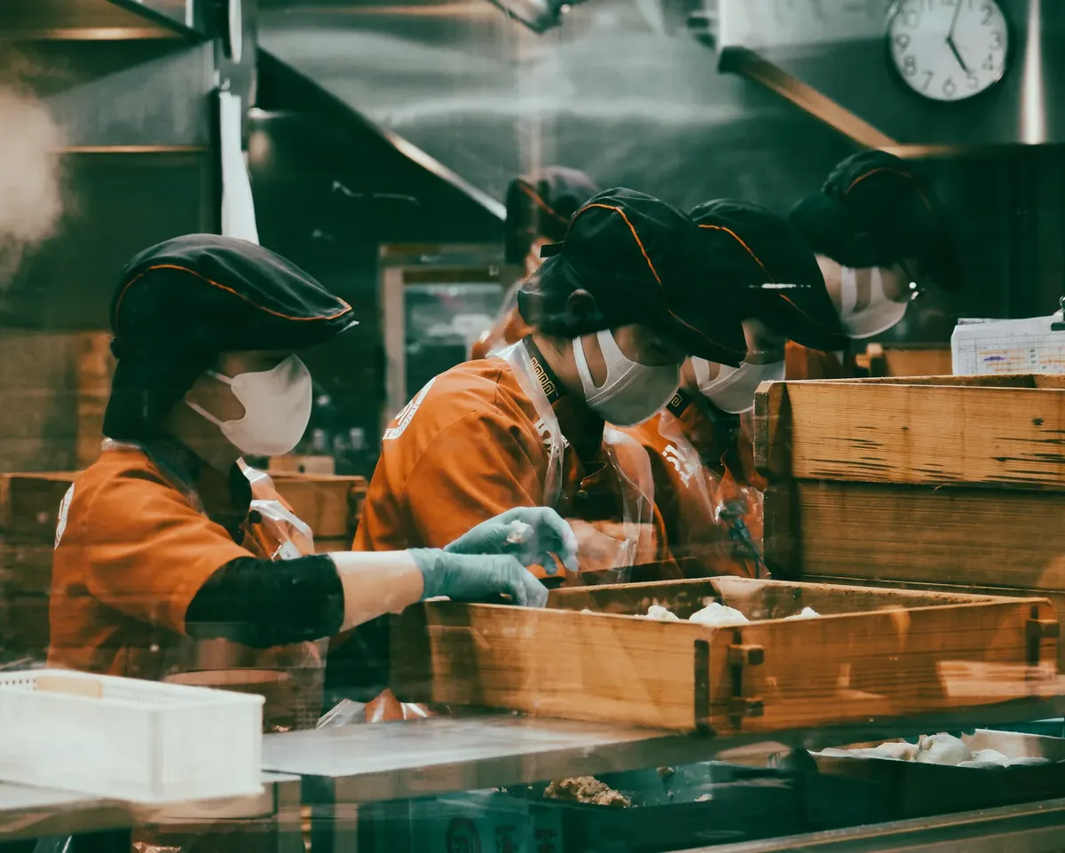 Four Japanese workers in a kitchen preparing traditional food in Tokyo, Japan.